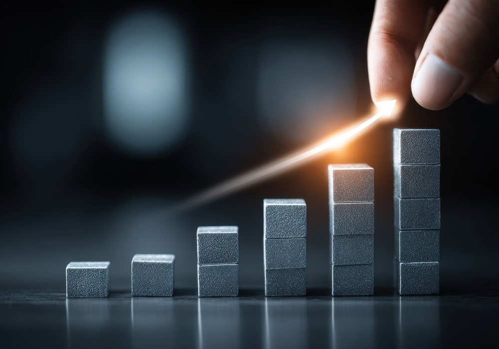 Hand placing an arrow pointing upward above stacked metallic blocks arranged in ascending order.