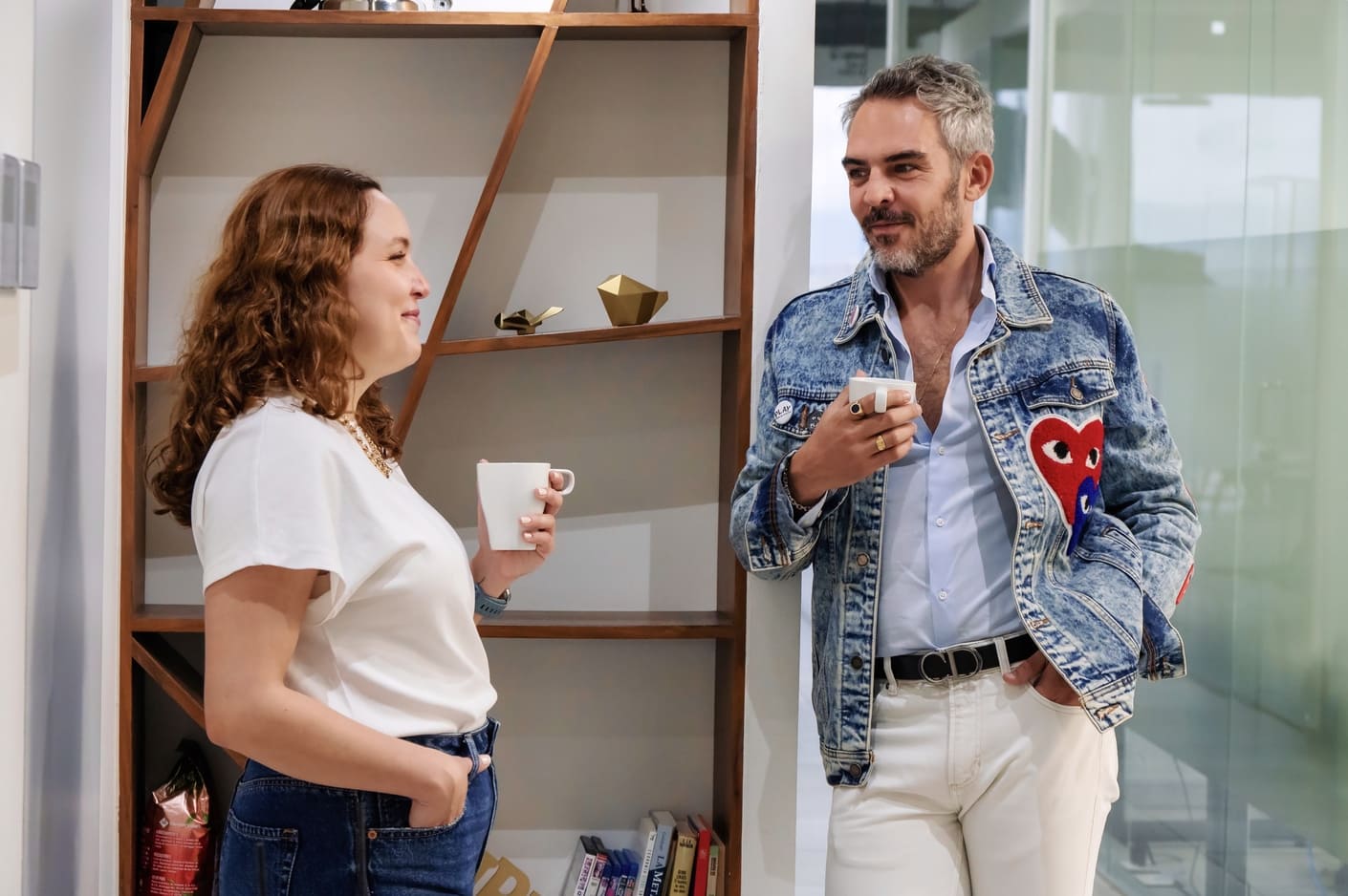 Francisco Cabrera y Valeria de Dios platicando y tomando un café en pasillo de oficina